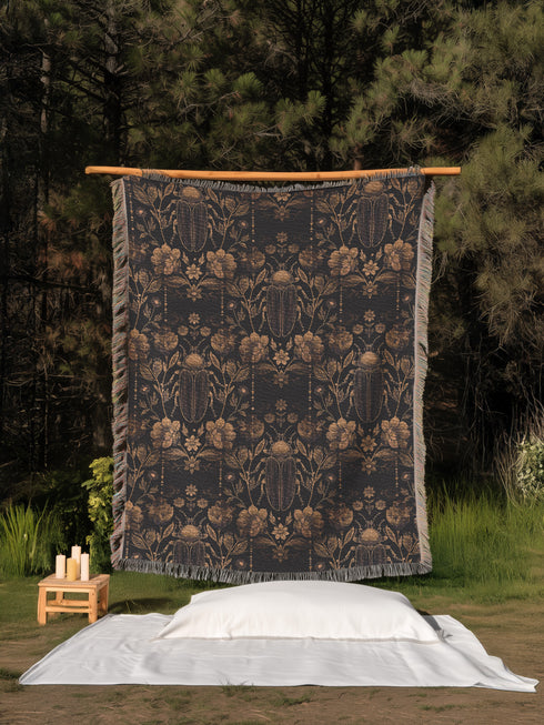 Black cotton throw blanket featuring woven bronze beetles and botanical motifs with multicolored fringe trim.